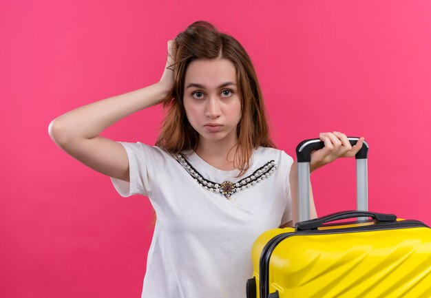 Foto gratuita fiducioso giovane viaggiatore ragazza che tiene la valigia e mettendo la mano sulla testa su uno spazio rosa isolato