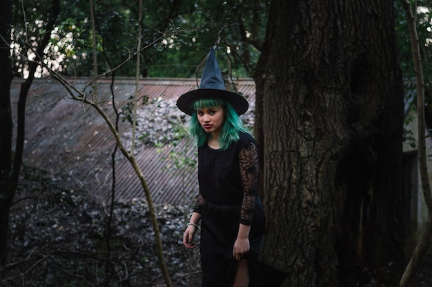Confident young witch in dark forest