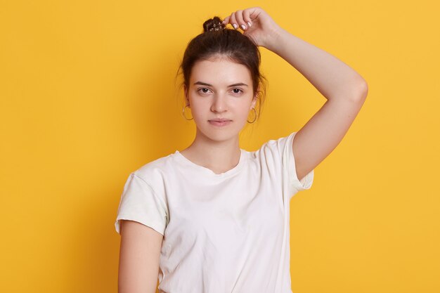 Confident young woman being photographed against yellow wall