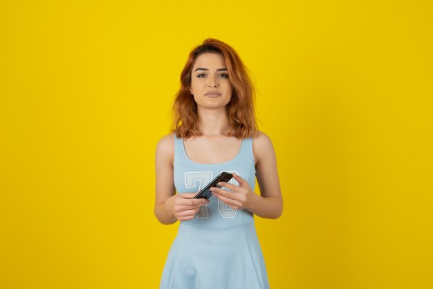 Confident young woman holding phone and looking at camera.