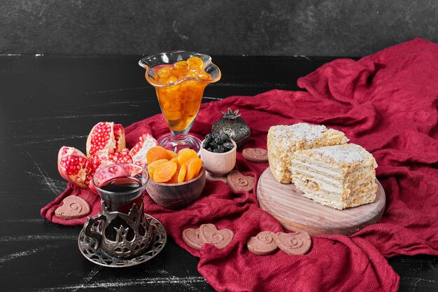 Confiture and cake slices on red towel with tea.