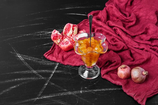 Confiture on red towel with pomegranate.