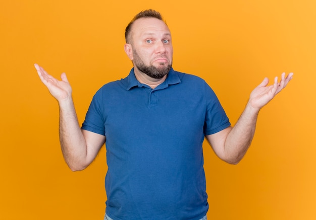 Confused adult slavic man showing empty hands  isolated on orange wall