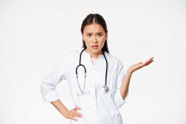 Confused asian woman doctor cant understand patient looking puzzled and annoyed raising hand up ques...