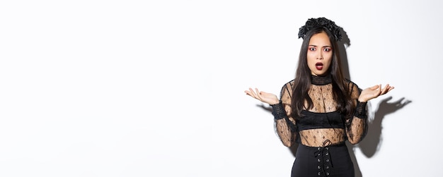 Confused asian woman in halloween costume looking clueless raising hands sideways and stare puzzled