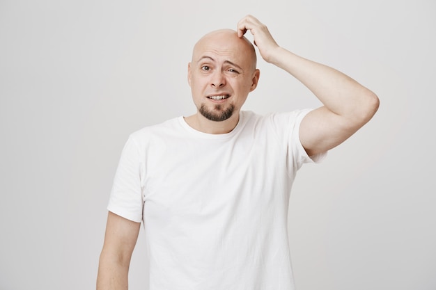 Confused bald middle-aged guy scratgh head puzzled