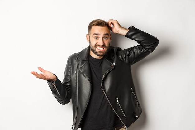 Free photo confused bearded guy in cool leather jacket shrugging, scratch head puzzled and clueless, standing