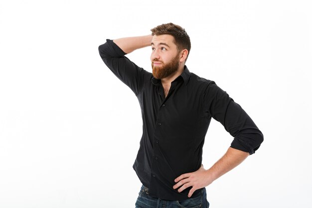 Confused bearded man in shirt holding head and looking away