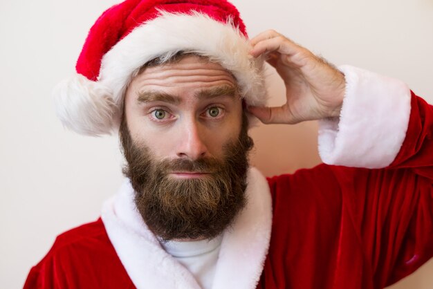 Confused bearded man wearing Santa Claus costume