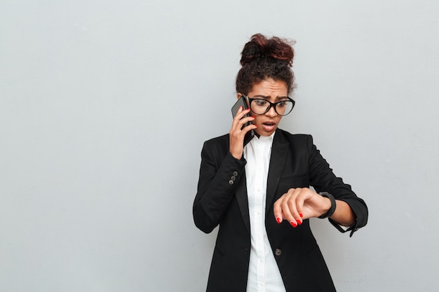 Confused business woman over grey wall looking aside