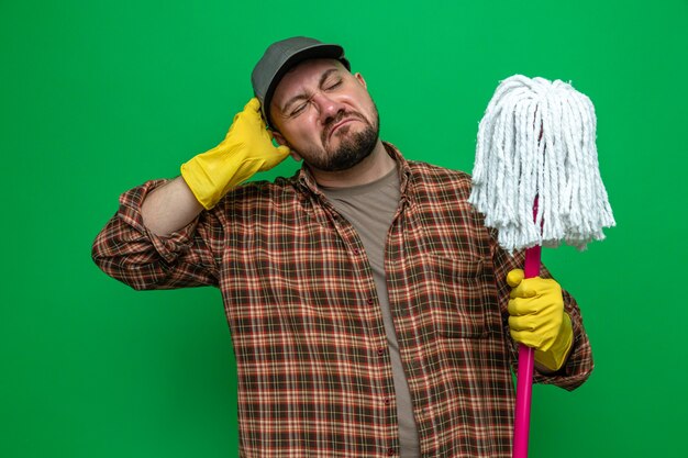 Confused cleaner man with rubber gloves holding and looking at mob 