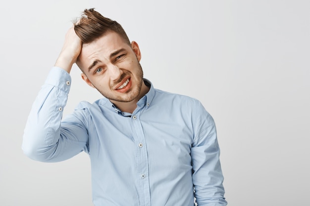 Confused and distressed young man looking puzzled, tossing hair and grimacing