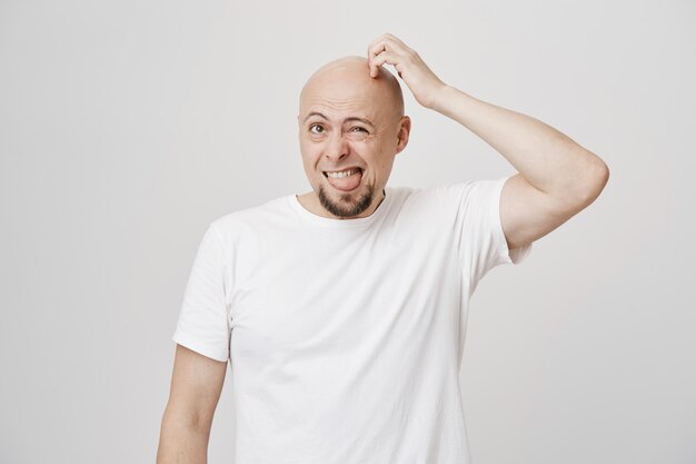Confused funny bald middle-aged guy scratgh head puzzled