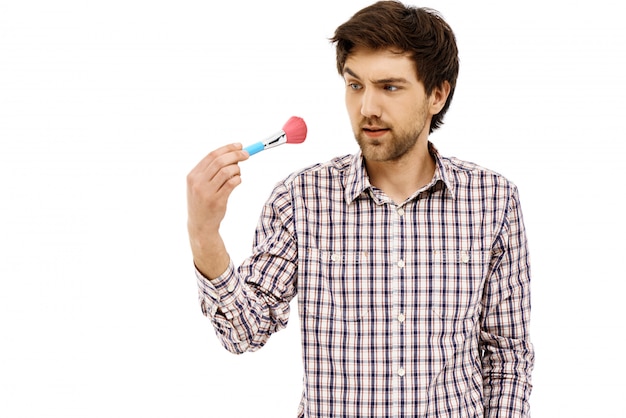 Confused guy staring at makeup brush