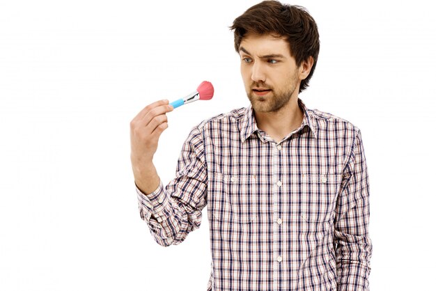 Confused guy staring at makeup brush