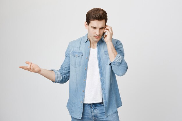 Confused handsome man having argument over phone