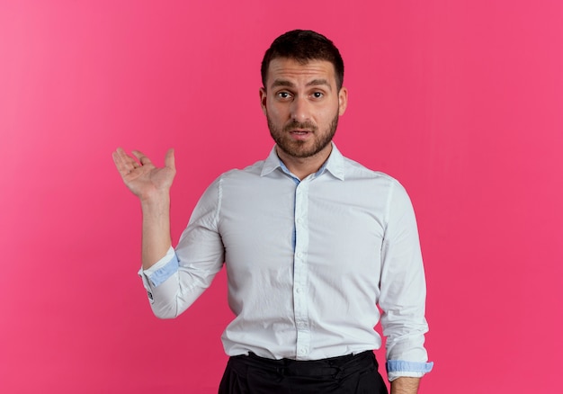 Confused handsome man points back with hand isolated on pink wall