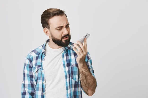 Смущенный мужчина смотрит на мобильный телефон после окончания разговора