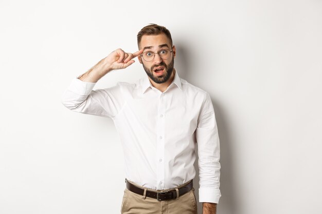 Confused man pointing at head, scolding employee, reaction on something strange, standing  white