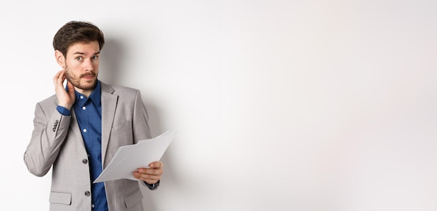 Free photo confused office worker in suit scratching beard and look clueless cant understand document holding p