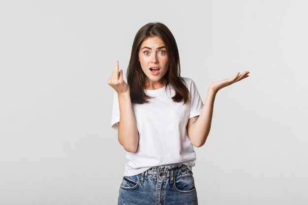 Confused and pissed-off brunette girl arguing about wedding, showing finger without ring.