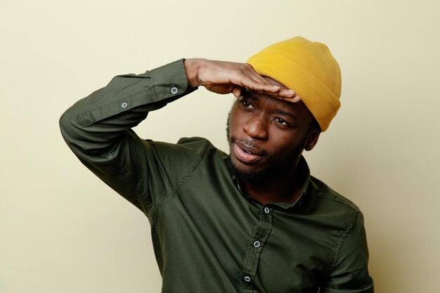 Confused putting hand on forehead young african american male in hat wearing green shirt isoloated on white background