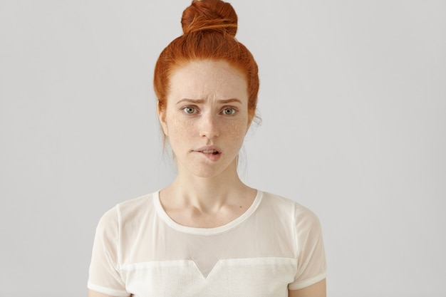 Confused or puzzled beautiful young Caucasian woman with ginger hair frowning