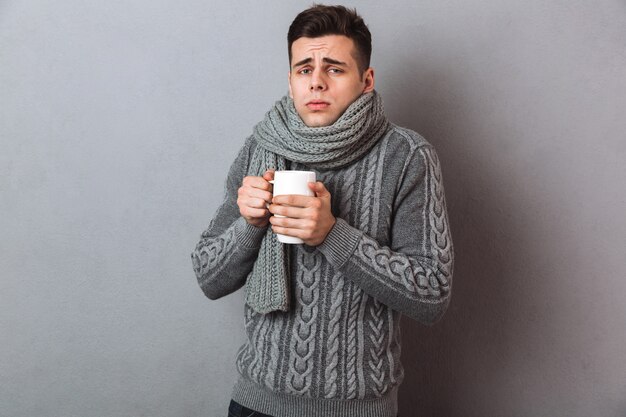 Confused Sick Man in sweater and scarf with serviette and spray having headache