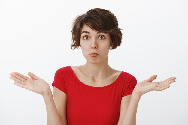 Confused silly woman shrugging, being unaware, have no idea