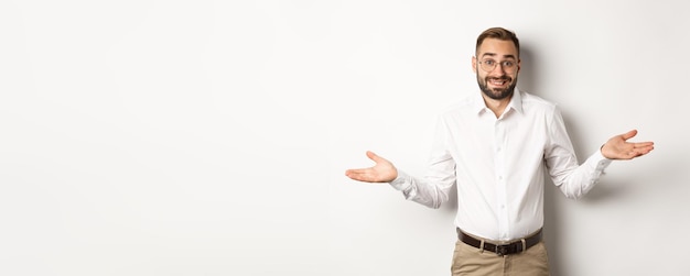 Free photo confused smiling businessman dont know shrugging and saying sorry standing over white background