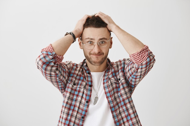 Confused and tensed young guy with glasses posing