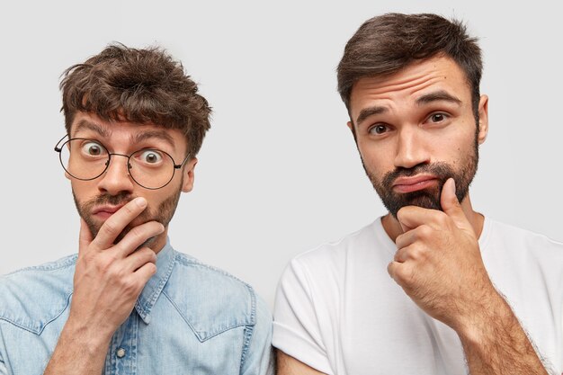 Confused two man colleagues frown faces with doubt, think over how overcome financial problems in company, have trendy haircuts