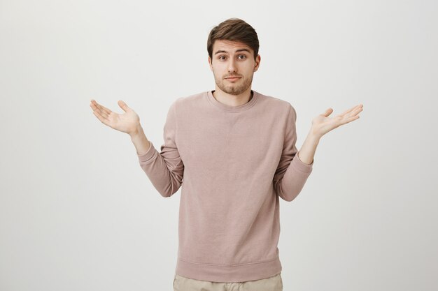 Confused and unaware handsome man with bristle, shrugging shoulders clueless