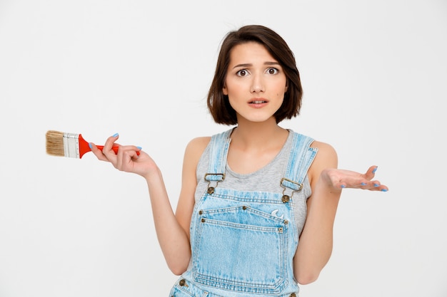 Confused woman hold painting brush and shrug clueless