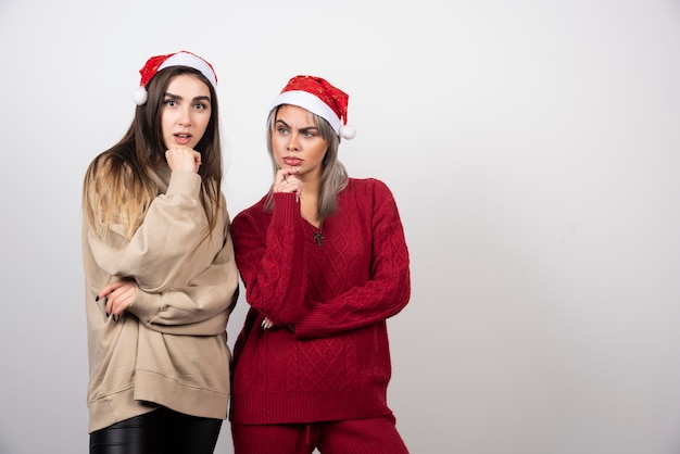 confused women friends posing isolated over white wall.