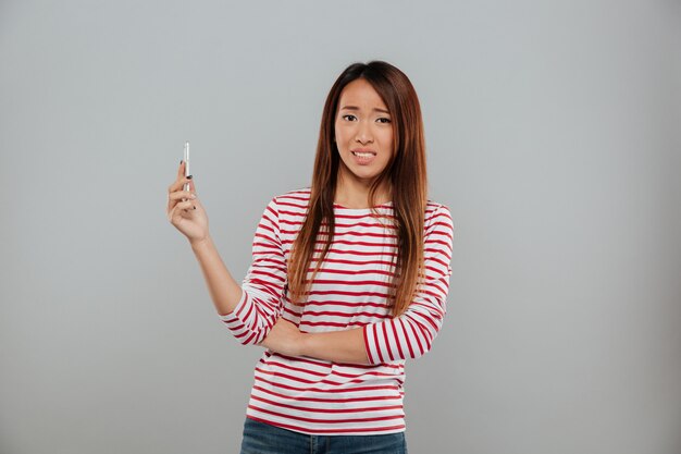 Confused молодая азиатская дама говоря по телефону