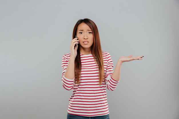電話で話している混乱している若いアジア女性