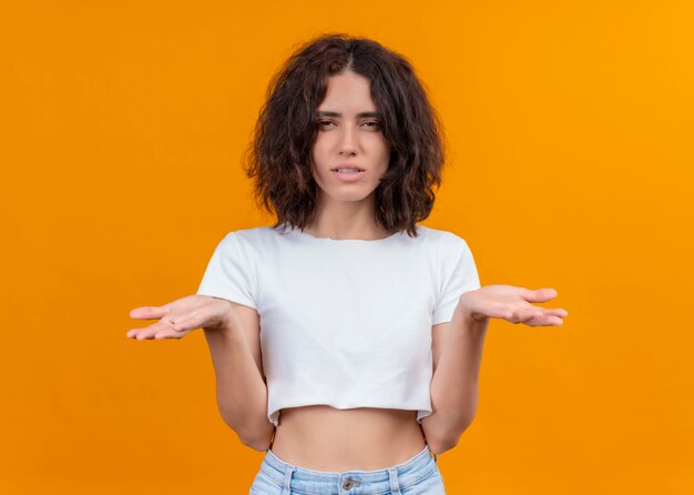 Confused young beautiful woman showing empty hands on isolated orange wall