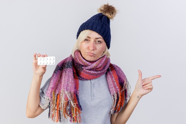 Confused young blonde ill slavic woman wearing winter hat and scarf