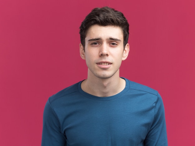 Confused young brunette caucasian boy looking at camera on pink