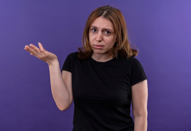 Free photo confused young casual woman showing empty hand on isolated purple space