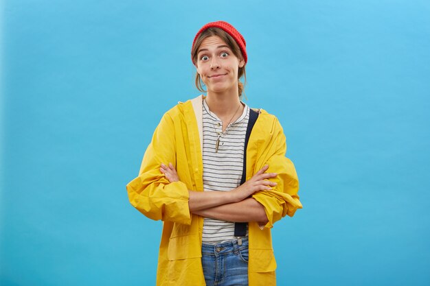 Confused young female wearing casual clothes standing crossed hands isolated over blue wall. Surprised woman looking with bugged eyes sorting her relationships with husband