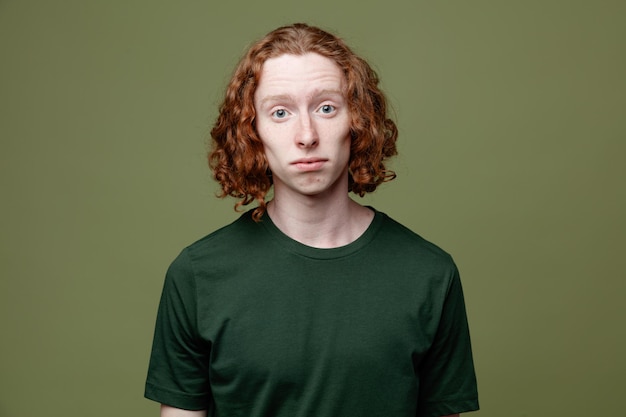 Confused young handsome guy wearing green t shirt isolated on green background