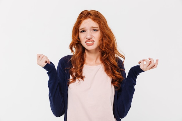 Free photo confused young redhead lady standing isolated