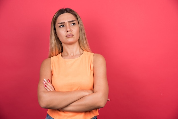 Confused young woman with crossed arms looking sideways.