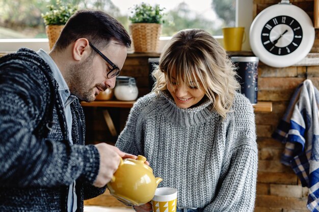 Considerate man pouring his wife a cup of tea in the kitchen