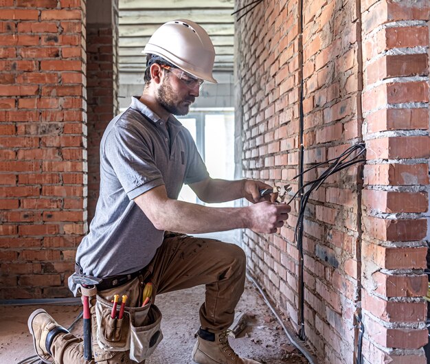 A construction electrician cuts a voltage cable during a repair