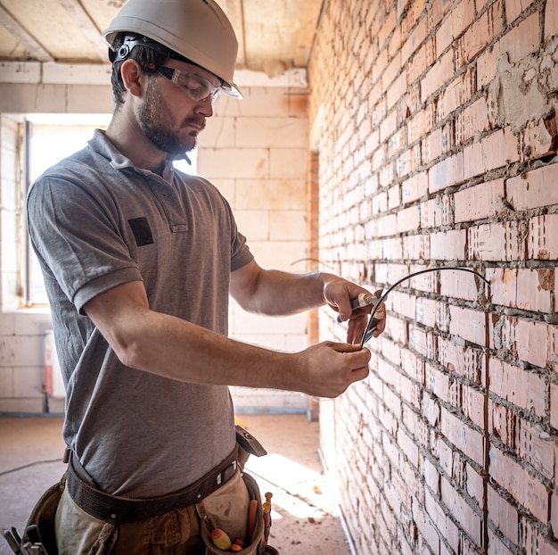 A construction electrician cuts a voltage cable during a repair