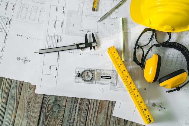 Construction plans with helmet and drawing tools on blueprints .