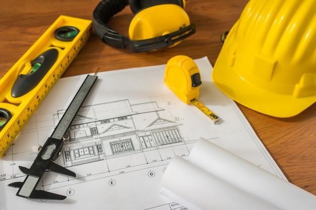 Construction plans with yellow helmet and drawing tools on bluep